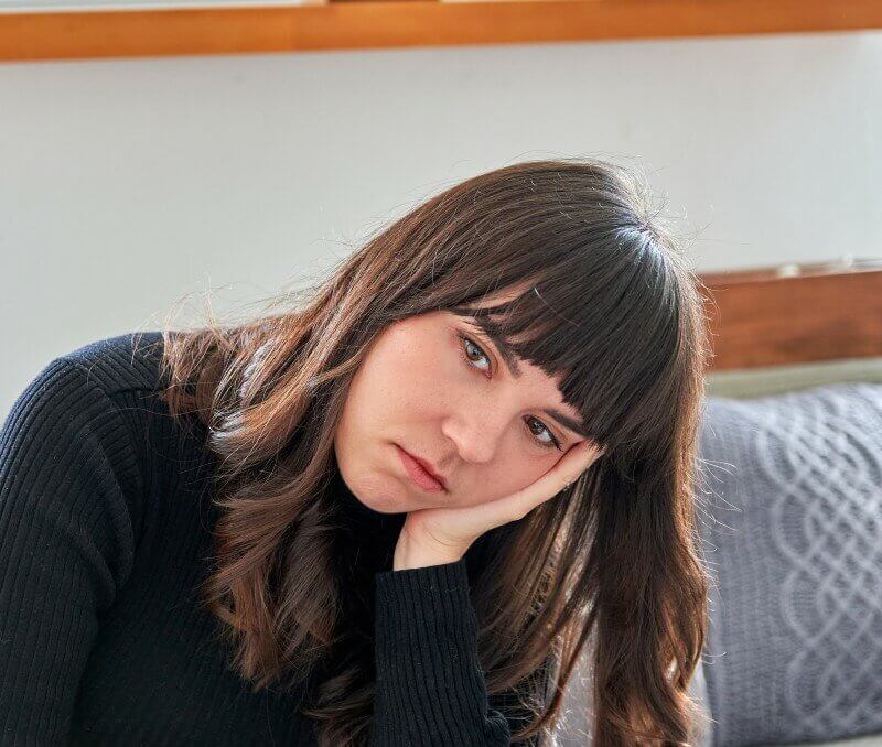 avoiding negative self talk lonely young woman sitting on couch holding her head young woman looking worried and depressed