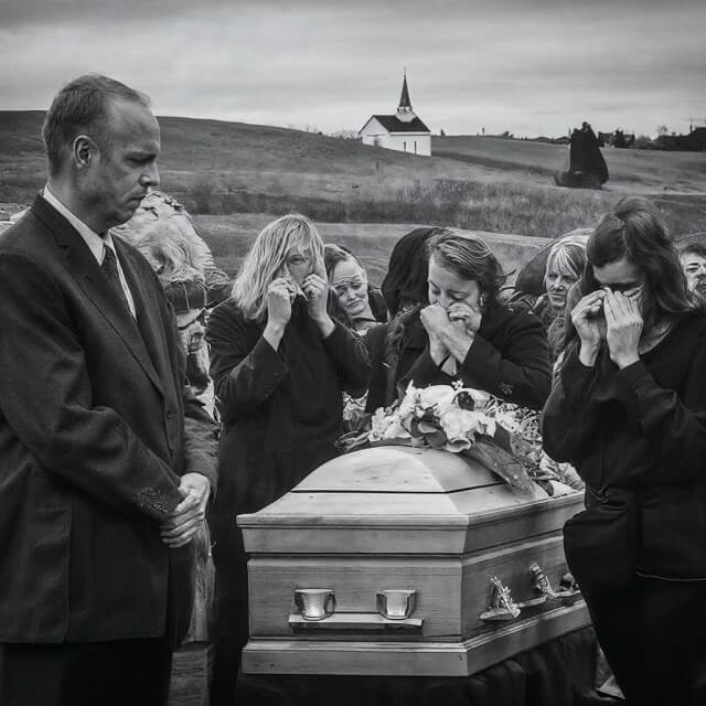 A photo of a funeral of country singer Toby Keith talking and listening to each other, symbolizing the importance of communication in the grieving process.