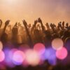 Concert crowd silhouettes raising phone lights under pink and purple stage lighting at a pop show