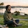 Young man taking a slow breath on the grass at Mission Bay in San Diego at sunrise, managing anxiety